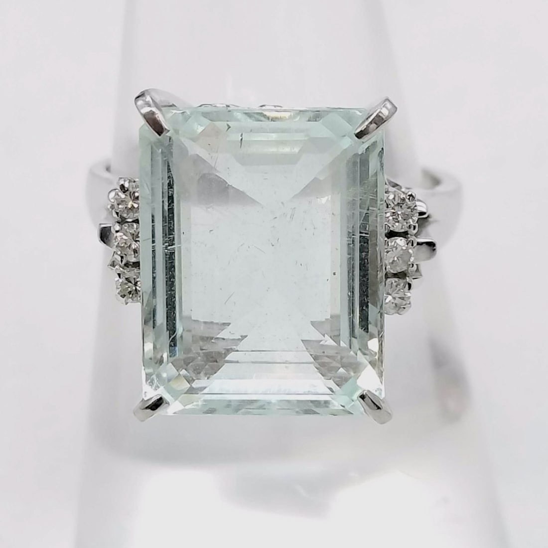 Platinum 7.17ct Aquamarine and .12ctw Diamond Cocktail Ring: This cocktail ring is crafted in platinum and features a large emerald-cut aquamarine. The primary stone is secured in a high-profile four-prong setting. The shoulders of the ring are accented with a 