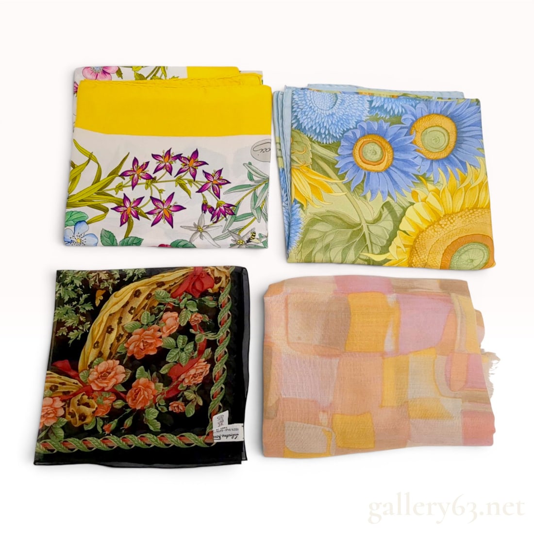 An Assortment of Designer and Fashion Scarves Including Gucci and Salvatore Ferragamo: An assortment of designer and fashion scarves featuring pieces by Gucci and Salvatore Ferragamo. The collection includes silk twill floral patterns and a lightweight abstract geometric scarf with frin