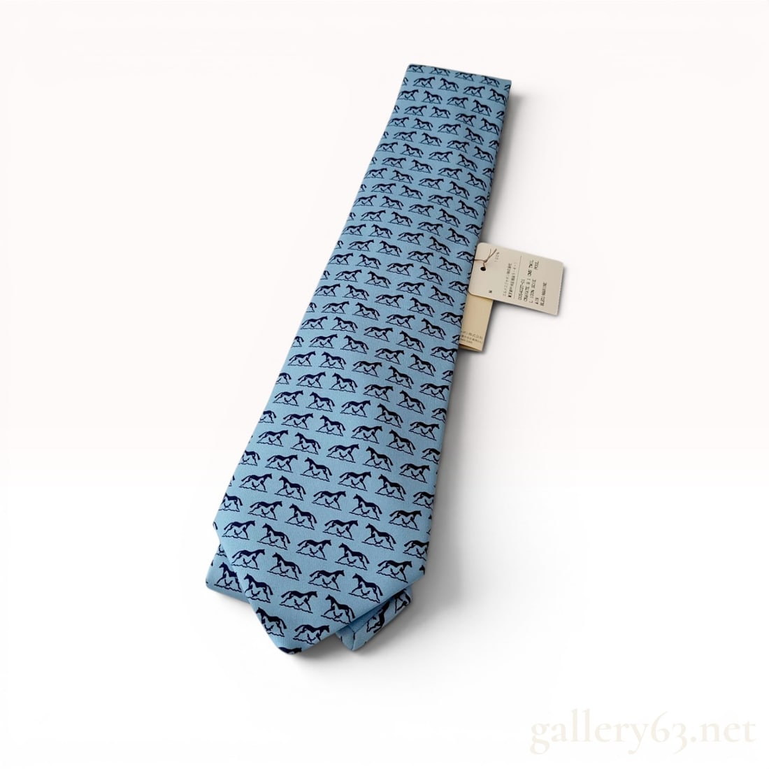 Hermes Silk Twill Necktie with Equestrian Motif with Box: Herm?¨s silk twill necktie with an equestrian motif, contemporary. Repeating navy blue horse pattern on a light blue silk ground with a coordinating logo-embroidered keeper loop. Interior printed mar