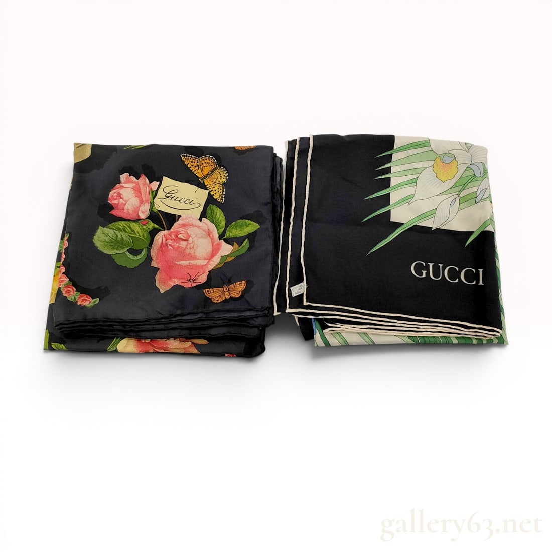Two Vintage Gucci Silk Scarves with Floral and Tropical Motifs: Two vintage Gucci square silk scarves, late 20th century, made in Italy. The first scarf features a black ground with various floral arrangements spelling "GUCCI" alongside butterfly accents