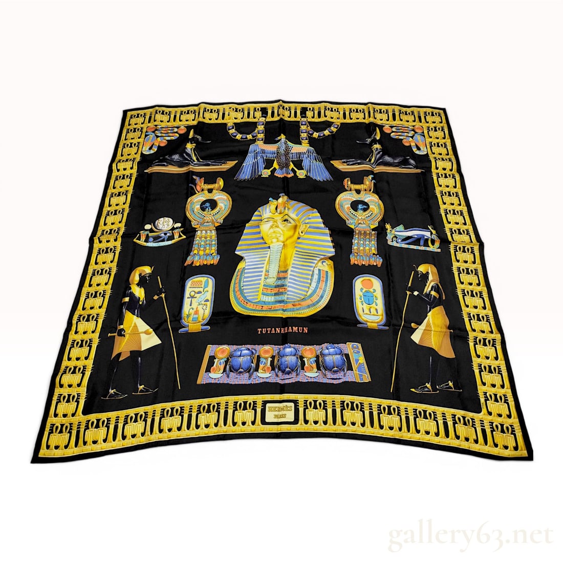 Hermes Tutankhamun Silk Scarf by Vladimir Rybaltchenko: Hermes silk scarf in the Tutankhamun pattern, designed by Vladimir Rybaltchenko and first issued in 1976. The design features the golden funerary mask of King Tutankhamun on a black ground, surrounded