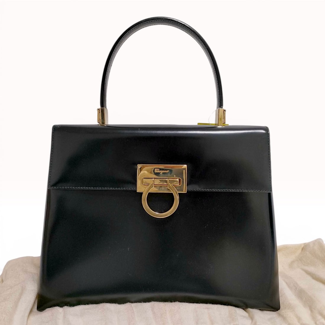 Salvatore Ferragamo Black Calfskin Iconic Top Handle Gancini Bag: Salvatore Ferragamo structured top handle bag in smooth black calfskin leather, late 20th century. The bag features a signature gold-tone Gancini flip-lock closure, gold-tone handle mounts, and four p