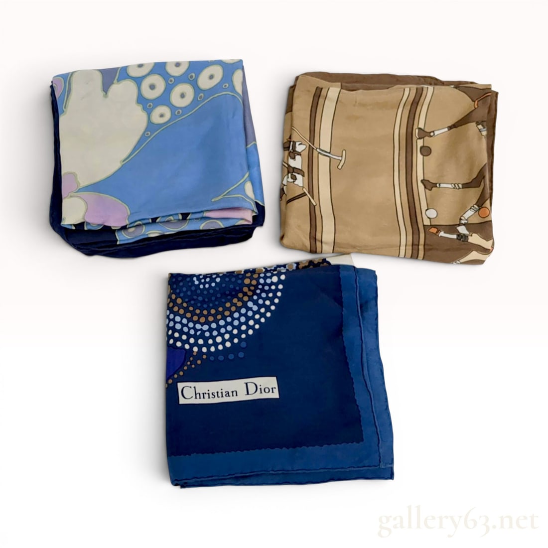 A Trio of Christian Dior Vintage Silk Scarves: Christian Dior vintage silk scarves, mid-to-late 20th century. Lot includes three silk twill scarves featuring a brown equestrian polo match scene, a navy blue scarf with concentric dotted geometric b