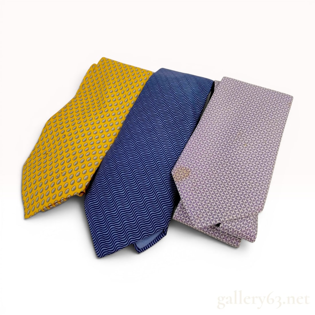 Three Hermes Silk Neckties: Three Herm?¨s designer neckties crafted from 100 percent silk. Patterns include a bright yellow ground with grey and silver oval dots, a navy blue ground with light blue horizontal wavy lines, and a 