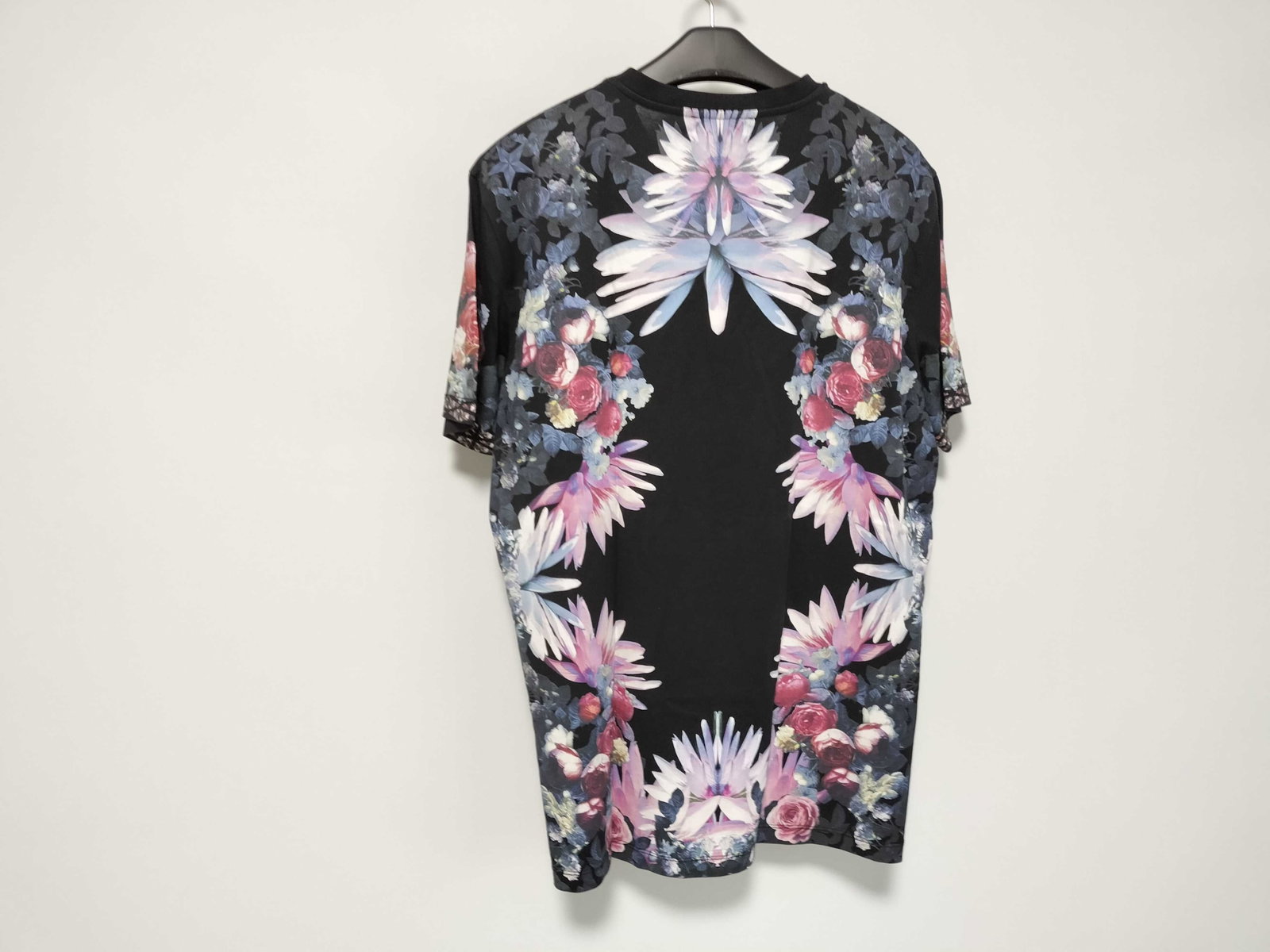 Givenchy Riccardo Tisci Black Floral Kaleidoscope Print T-Shirt: This short-sleeved crew neck t-shirt is by Givenchy, featuring a design characteristic of the Riccardo Tisci era. The garment displays a symmetrical, mirrored floral print composed of roses and lilies