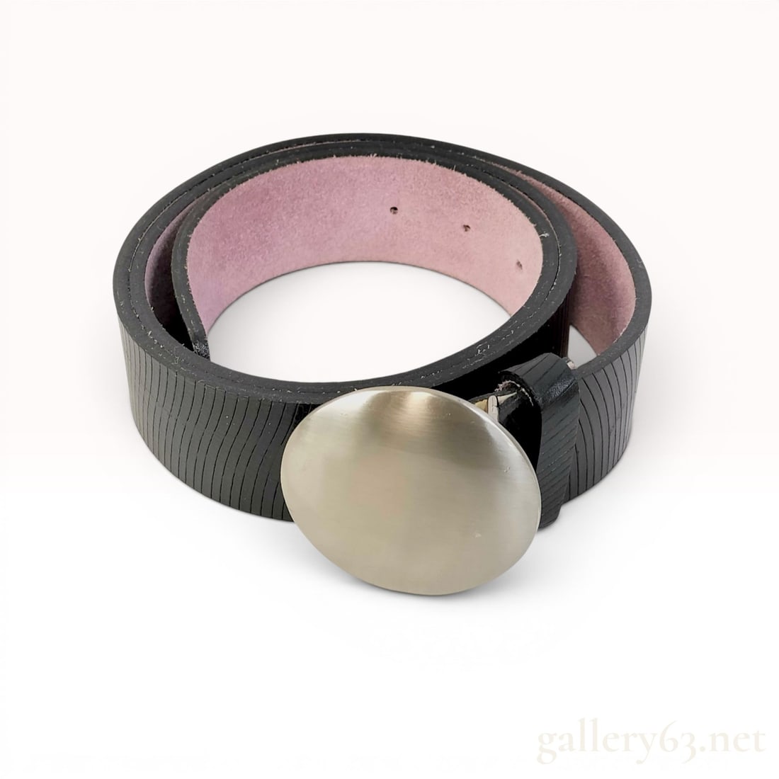 Issey Miyake Fete Textured Leather Belt with Circular Buckle: Issey Miyake Fete leather belt featuring a black strap with a fine vertical ribbed texture and a contrasting light pink suede interior. The piece is finished with a substantial, circular domed buckle 