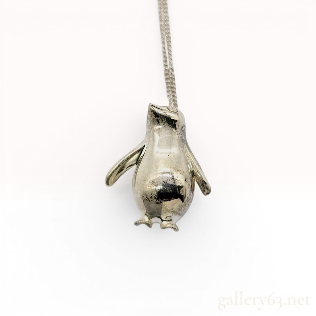 Tiffany & Co. Sterling Silver Penguin Pendant Necklace: This Tiffany & Co. pendant necklace features a three-dimensional penguin charm crafted from sterling silver. The pendant is designed with a polished exterior and a hollowed-out reverse. It is susp