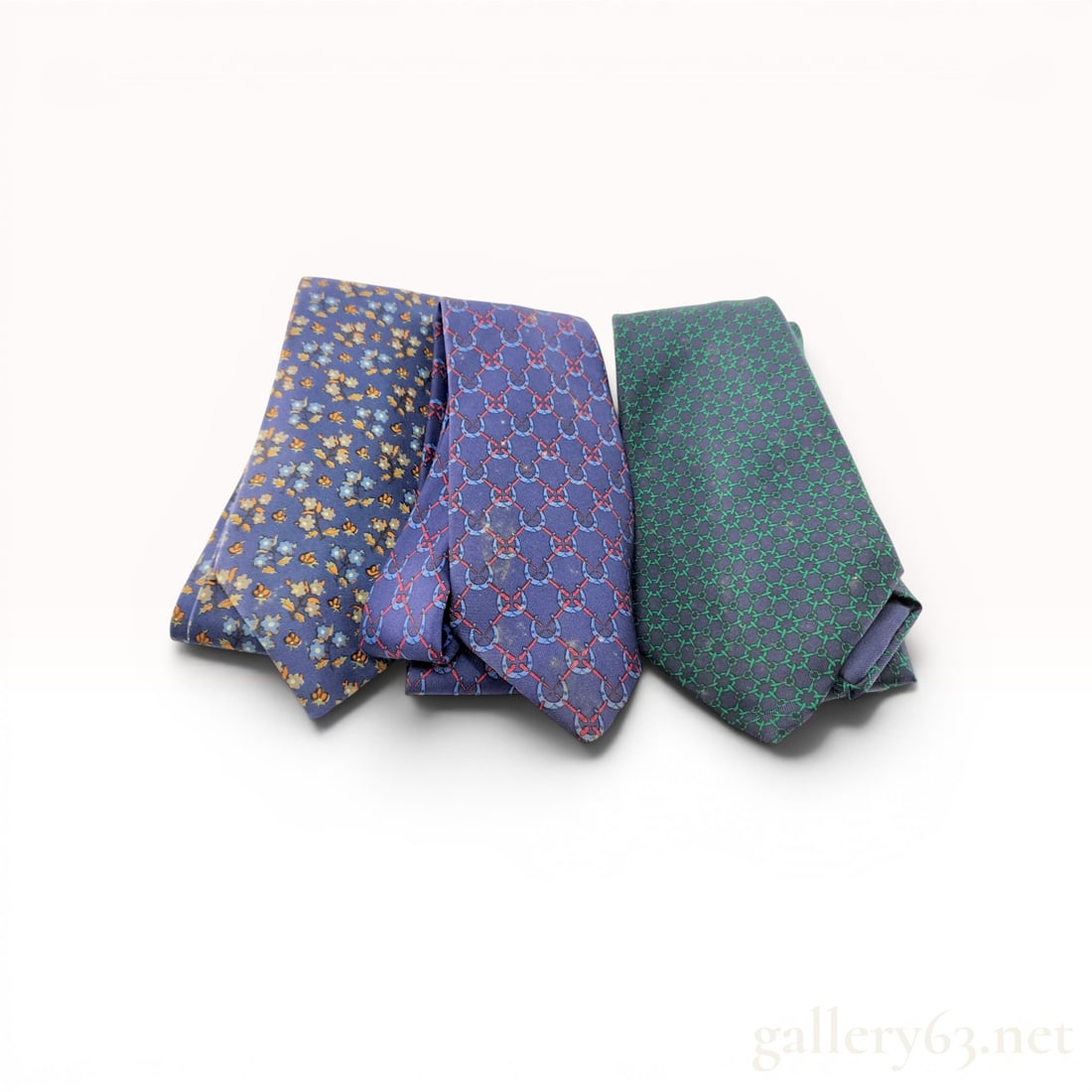 A Trio of Hermes Paris Silk Neckties: Hermès Paris trio of men's neckties, late 20th century. The collection features a navy floral ditsy print, a blue horseshoe pattern with red lattice, and a charcoal tie with green interlocking 
