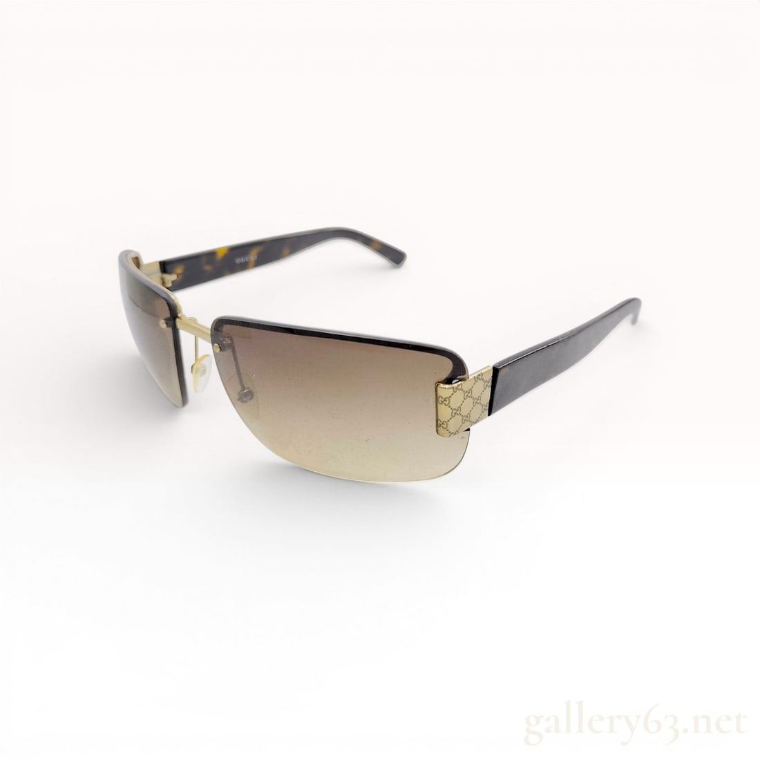 Gucci GG 1798/N/S Rimless Brown Gradient Sunglasses: A pair of rimless designer sunglasses by Gucci, model GG 1798/N/S. The eyewear features rectangular lenses with a brown gradient tint. The gold-tone metal bridge and hinges are detailed with an engrav