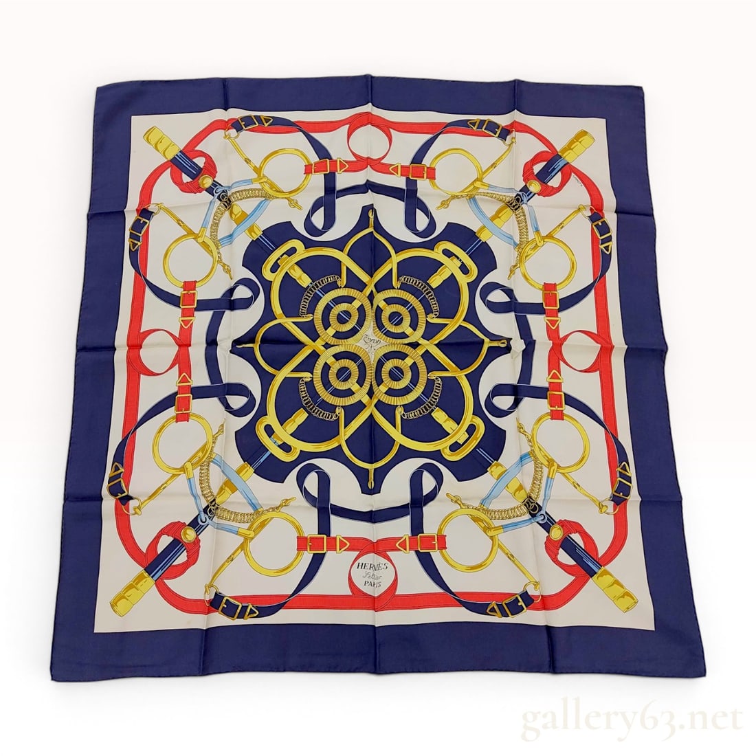 Hermes Eperon d'Or Silk Scarf by Henri d'Origny: This is an authentic Hermès silk twill scarf in the Eperon d'Or pattern, designed by Henri d'Origny. The design features a classic symmetrical equestrian motif of interlocking leather straps, m