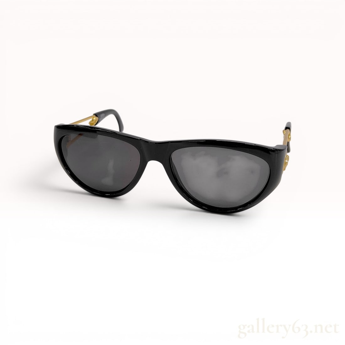 Gianni Versace Mod 427 Safety Pin Cat-Eye Sunglasses: Gianni Versace vintage cat-eye sunglasses, Model 427, circa 1990s. Black acetate frames with grey-tinted lenses feature signature gold-tone metal safety pin temples and Medusa head medallions. Interio