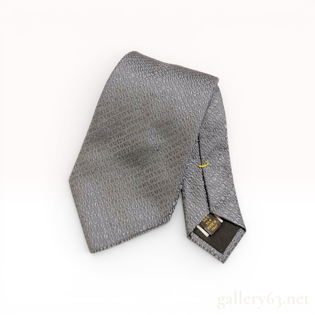 Louis Vuitton Monogram Script Silk Necktie in Grey: A Louis Vuitton men's necktie crafted from 100 percent silk. The tie features a tonal jacquard weave with a repeating diagonal pattern of the Louis Vuitton script. The color is a charcoal grey with li