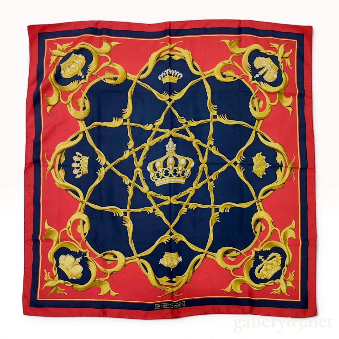 Hermes Couronnes Silk Gavroche Scarf: Hermès silk twill Gavroche scarf in the Couronnes pattern, originally designed by Julia Abadie. The design displays intricate royal crowns and golden foliate scrolls on a navy blue field within