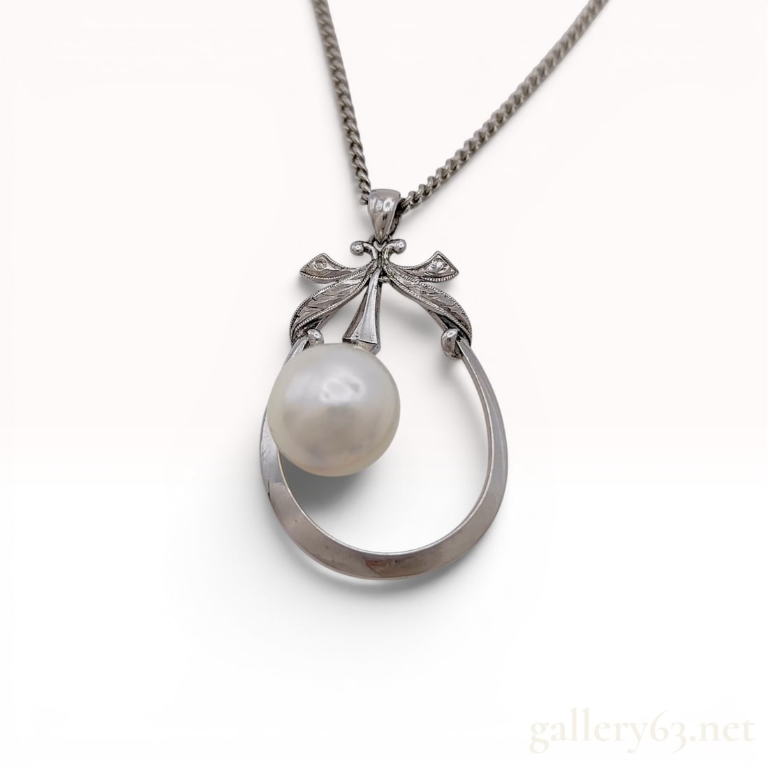 Mikimoto Silver and Cultured Pearl Pendant Necklace: Mikimoto cultured pearl pendant necklace featuring a single white pearl suspended within an open teardrop-shaped frame with stylized floral flourishes. The silver pendant is paired with a fine curb-li