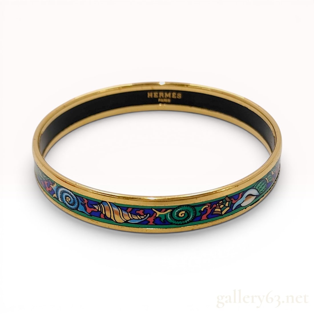 Hermes Gold Plated and Printed Enamel Seashell Motif Narrow Bangle Bracelet with Box: This Hermes narrow bangle bracelet features a vibrant printed enamel design with a marine theme. The exterior is decorated with a continuous frieze of stylized seashells, including nautilus and conch 