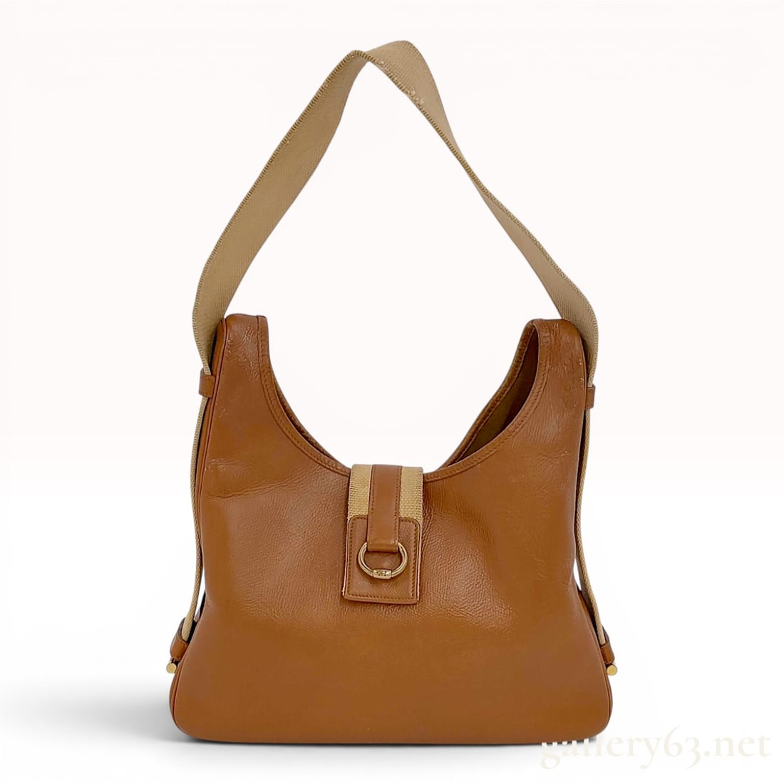 Hermes Tsako Leather and Canvas Shoulder Bag: This Hermes Tsako shoulder bag is a vintage hobo-style piece crafted from tan grained leather and beige canvas webbing. The bag features a characteristic U-shaped top silhouette with a central leather