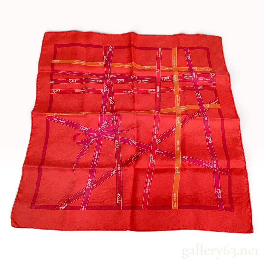 Hermes Bolduc Ribbon Silk Gavroche Scarf: An Hermes silk gavroche scarf in the Bolduc pattern. This accessory is made from 100% silk and features hand-rolled hems. The design depicts a variety of ribbons in shades of orange, pink, and burgund