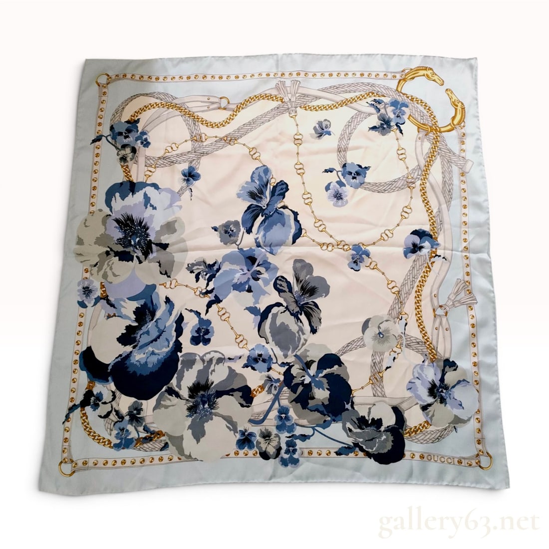Gucci 90cm Square Silk Twill Scarf with Floral and Equestrian Motif: This is a square silk twill scarf manufactured by the Italian luxury brand Gucci. The print features a central cream field adorned with large flowers in shades of navy blue, slate blue, and charcoal g