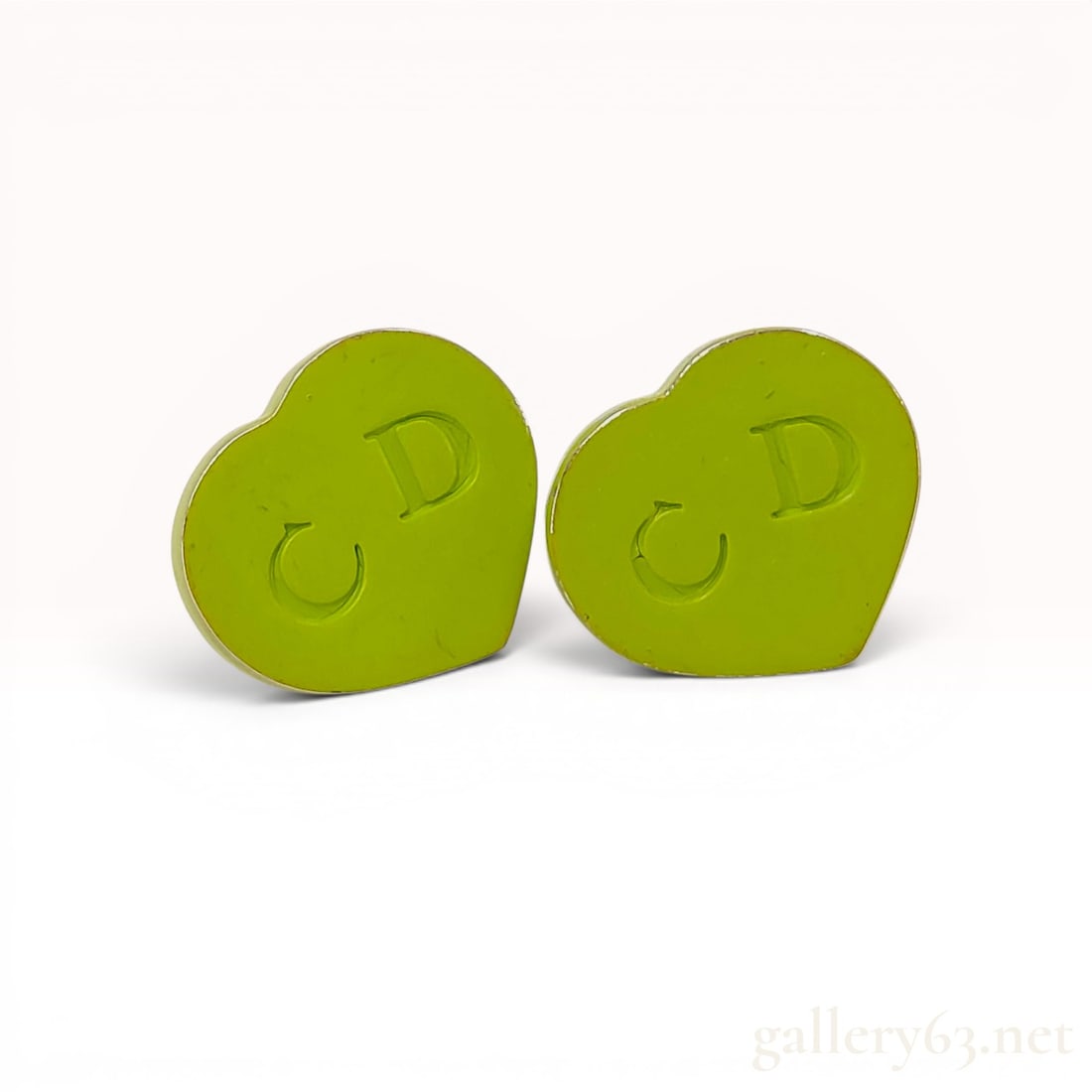 A Pair of Christian Dior Silver-Tone and Lime Green Enamel Heart Stud Earrings: A pair of vintage designer stud earrings by Christian Dior. Each earring is designed in a heart shape featuring a lime green enamel face embossed with the CD monogram logo. The earrings are equipped w