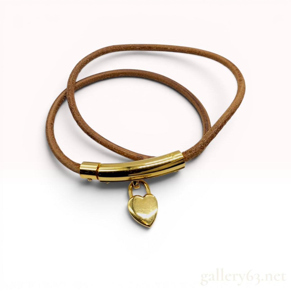 Hermes Viviride Heart Padlock Double-Wrap Leather Bracelet: This Hermes Viviride double-wrap leather bracelet features a brown leather cord and polished yellow gold-toned metal components. The design centers on a curved metal bar with an integrated peg-and-soc