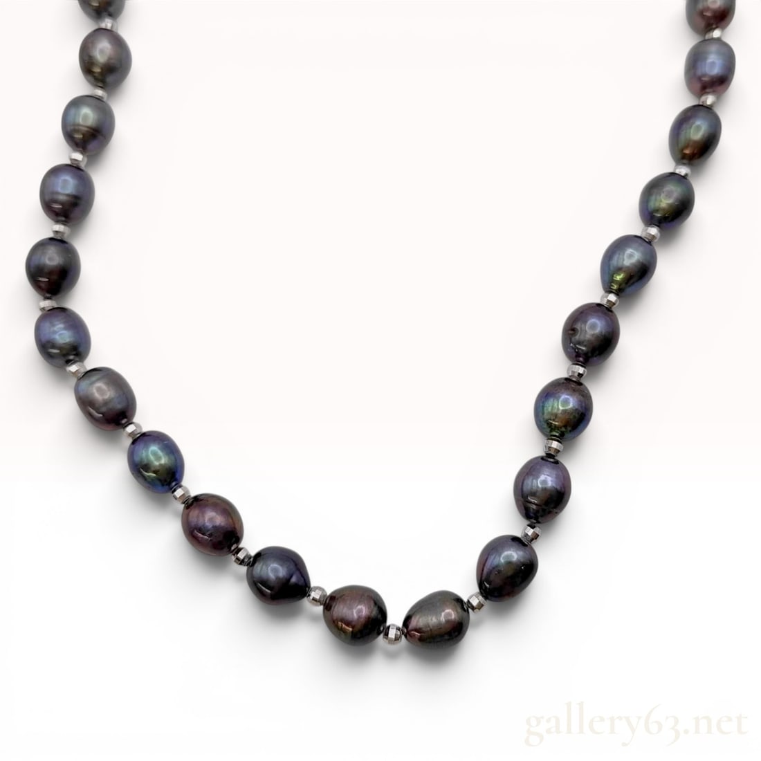 Sterling Silver and Black Peacock Freshwater Cultured Pearl Necklace: This necklace features a single strand of black freshwater cultured pearls characterized by a peacock orient with iridescent overtones of green, blue, and purple. The pearls are oval-to-potato shaped 