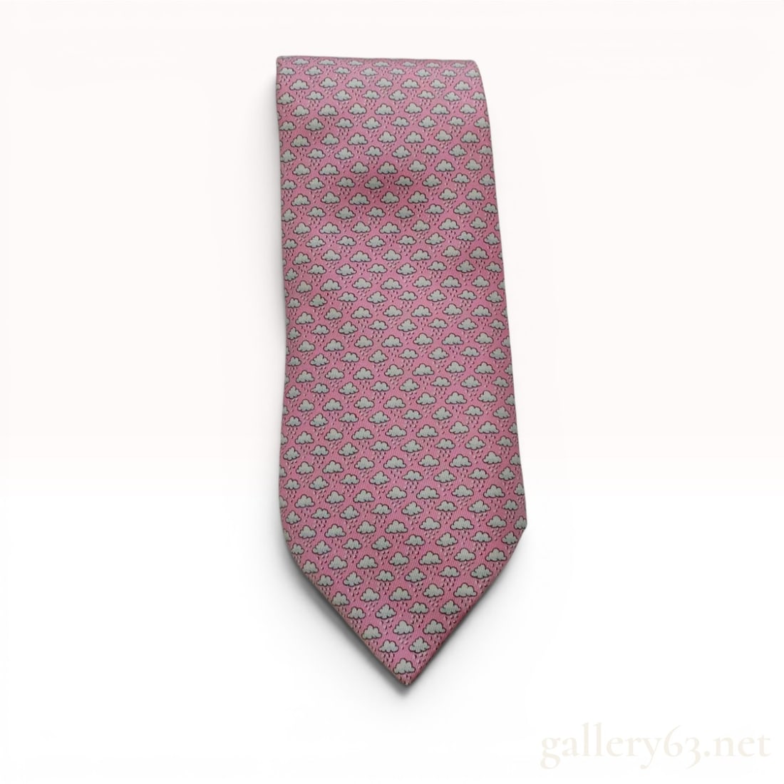 Hermes Pink Silk Rain Cloud and Umbrella Print Necktie: An authentic Hermes silk necktie featuring a whimsical two-sided print design on a pink ground. The main body of the necktie displays a repeating pattern of white rain clouds with light blue droplets.