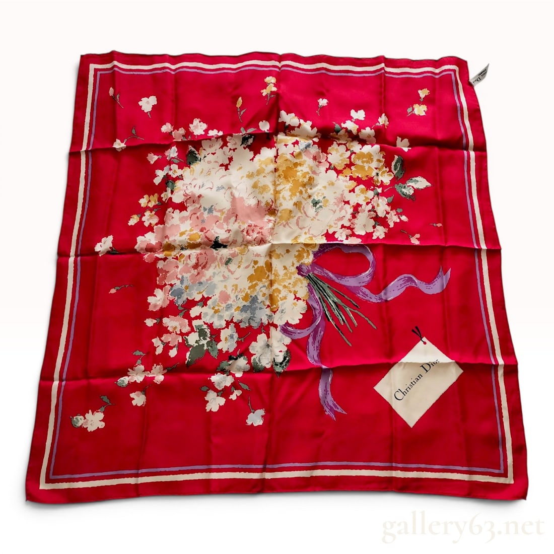 Christian Dior Floral Bouquet Silk Scarf with Red Ground: This 100 percent silk scarf from the Christian Dior Echarpes line features a large, central bouquet of white and golden-yellow flowers tied with a cascading lavender ribbon. This central motif is set 