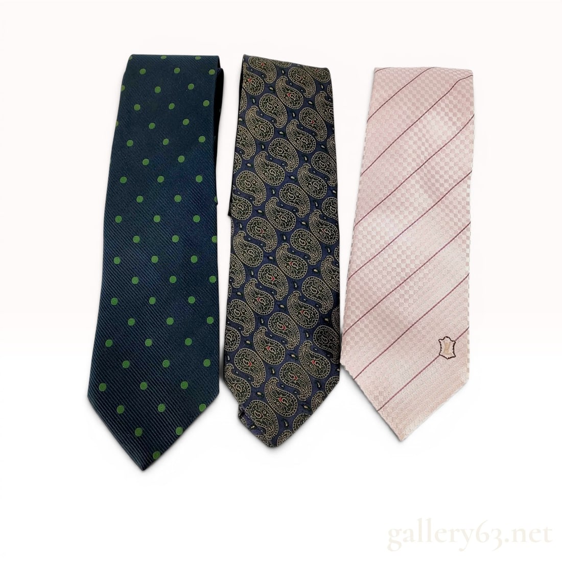A Trio of Designer Silk Neckties Including Chanel and Louis Vuitton: This lot features three designer silk neckties from Chanel and Louis Vuitton. The first tie is a Chanel silk necktie with a navy blue ground and green polka dot pattern. The fabric exhibits a diagonal