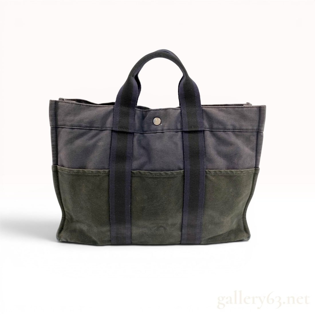 Hermes Fourre-Tout MM Canvas Tote Bag: This Hermes Fourre-Tout MM (Medium Model) tote bag is constructed from cotton canvas in a two-tone navy blue and olive green colorway. The design features six exterior slip pockets, three on each side