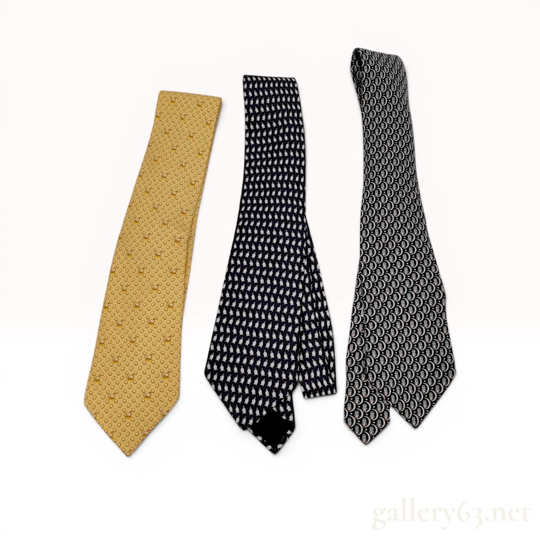 A Trio of Hermes Silk Neckties: This lot consists of three professional men's neckties from Hermes. Each necktie is crafted from 100 percent silk and features a unique repeating whimsical motif. The first tie is a gold/yellow color 