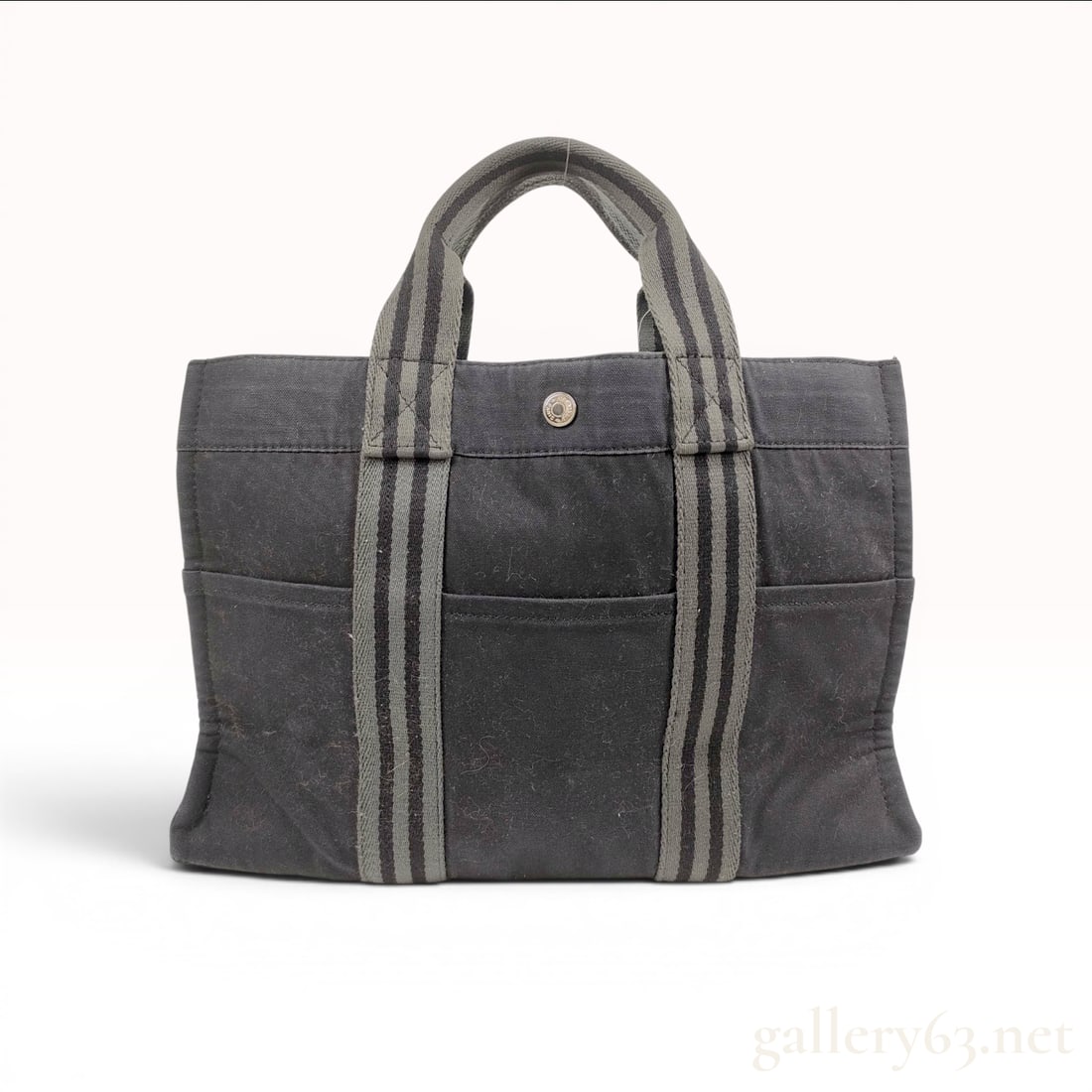 Hermes Fourre-Tout Canvas Tote Bag PM: A Hermes Fourre-Tout tote bag, size PM (Petit Modele), crafted from durable charcoal black canvas. The bag features a classic minimalist design with vertical grey and black striped webbing straps that