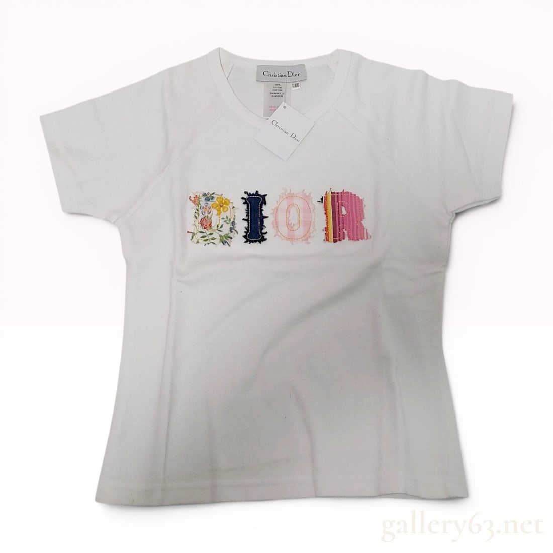 Christian Dior Youth White Raglan T-Shirt with Patchwork Logo, Size 12 ANS: A youth short-sleeved white cotton t-shirt by Christian Dior featuring raglan-style construction. The front displays a mixed-media applique of the brand name DIOR in patchwork letters. The D is a mult