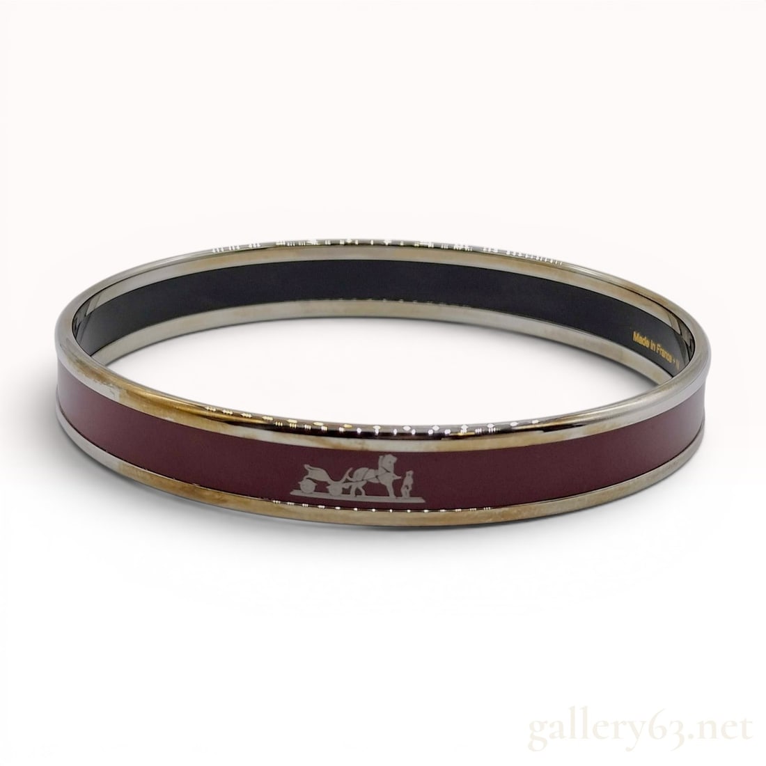 Hermes Narrow Caleche Enamel Bangle Bracelet: An Hermes Caleche enamel bangle bracelet featuring a burgundy enamel inlay on a silver-toned metal frame. The narrow band is decorated with the signature silver-toned horse and carriage (Caleche) moti