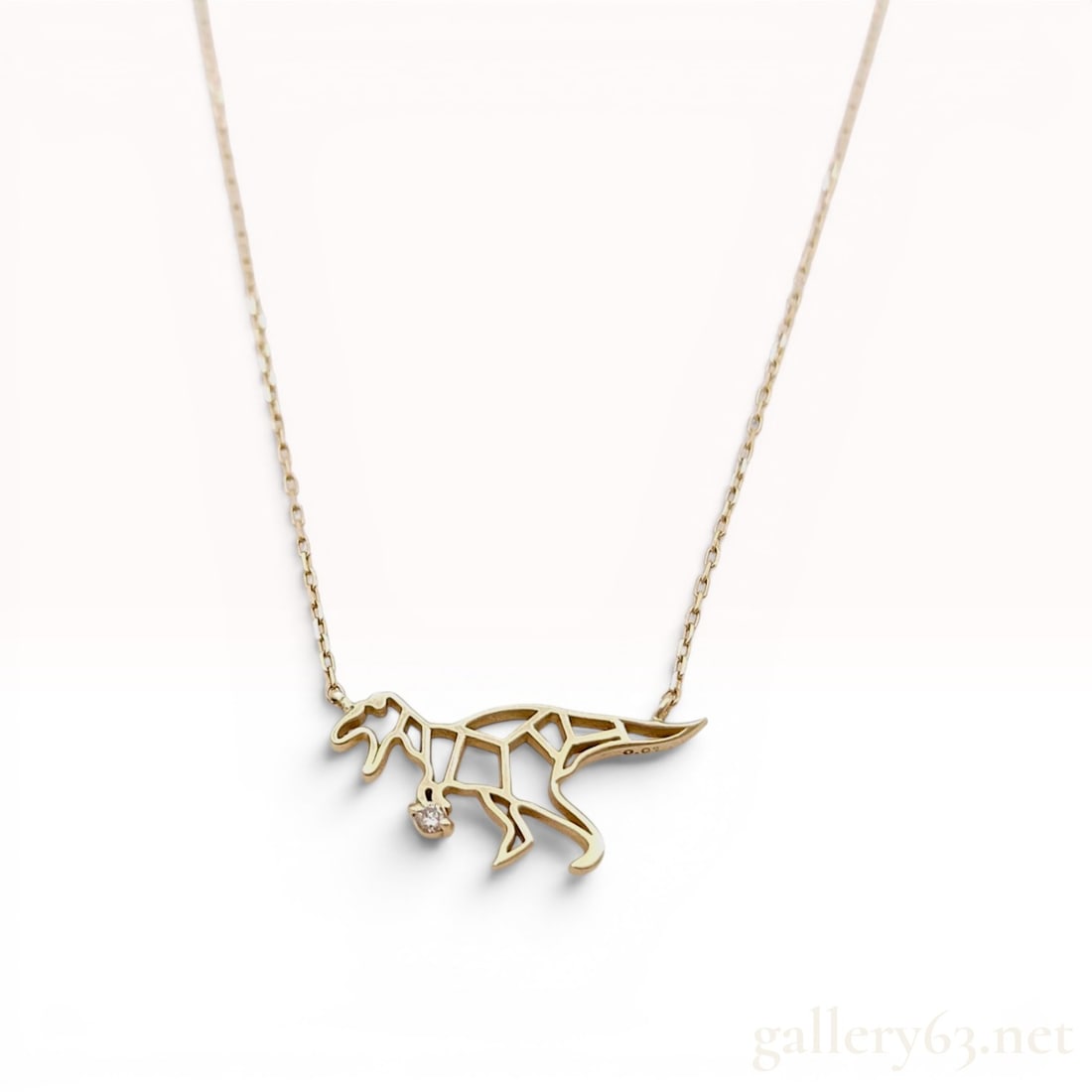 10K Yellow Gold Geometric Dinosaur Pendant Necklace with Diamond Accent: This 10k yellow gold pendant necklace features a stylized, geometric representation of a Tyrannosaurus Rex. The openwork pendant is designed in an origami-inspired style and holds a single, small, rou