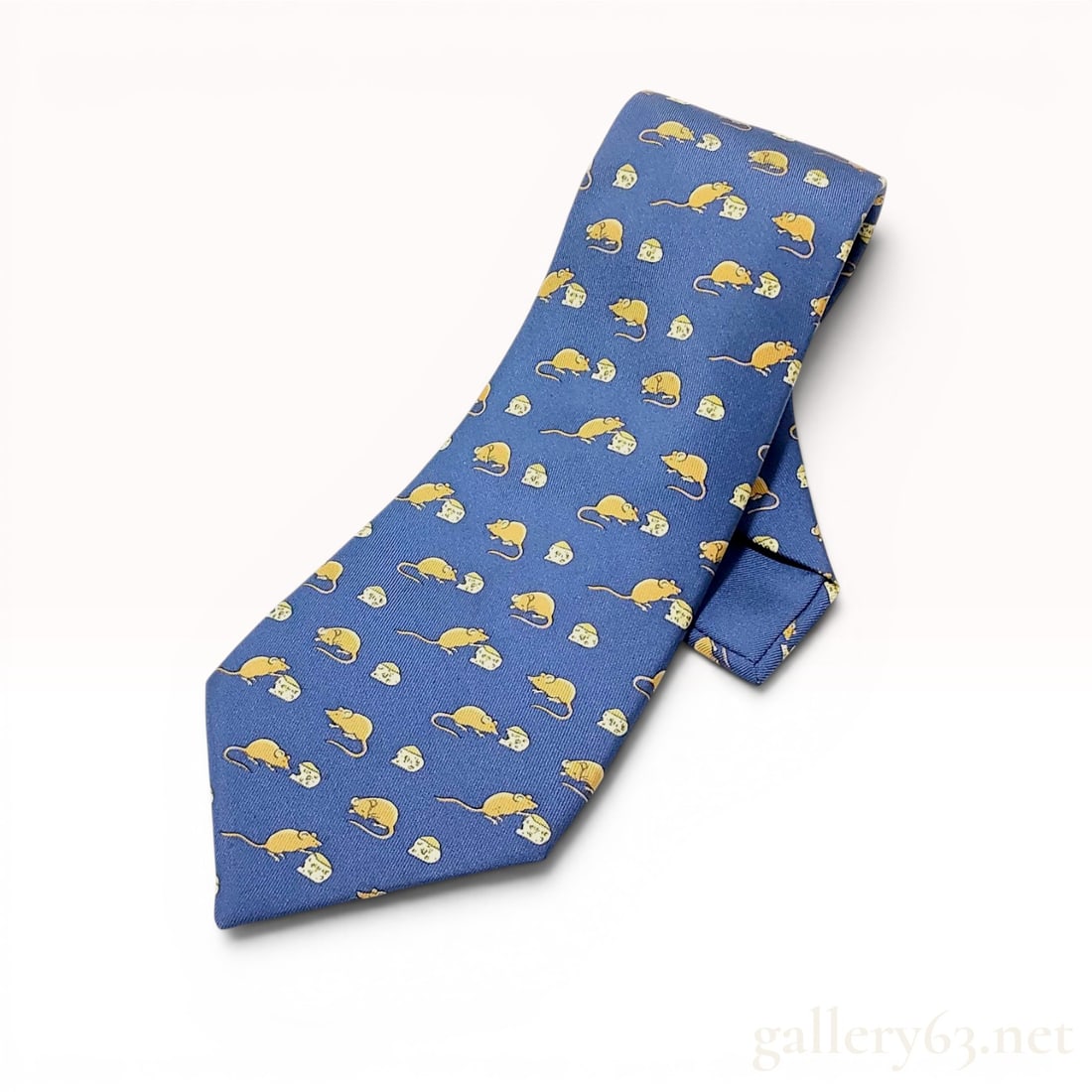 Hermes Silk Necktie Whimsical Mice and Cheese Pattern 7605 SA: This Hermes necktie is constructed from 100 percent silk and features a repeating novelty pattern of small yellow mice and wedges of Swiss cheese on a blue ground. The front of the wide blade shows a 
