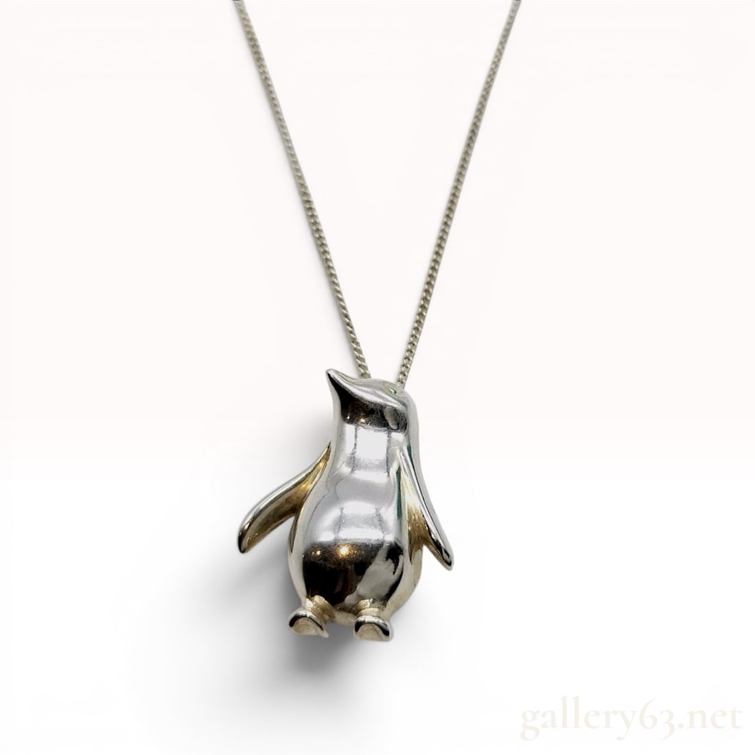 Tiffany and Co. Sterling Silver Penguin Pendant Necklace: This necklace features a sterling silver pendant modeled as a three-dimensional penguin with a hollowed-out reverse. The pendant is suspended from a curb link chain that terminates in a spring ring cl