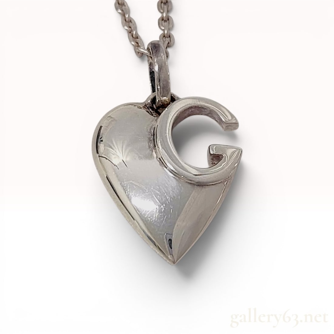 Gucci Interlocking G Heart Sterling Silver Pendant Necklace with Box: This necklace features a Gucci interlocking G heart pendant crafted from polished .925 sterling silver. The pendant presents a three-dimensional heart form with an integrated interlocking G motif. The