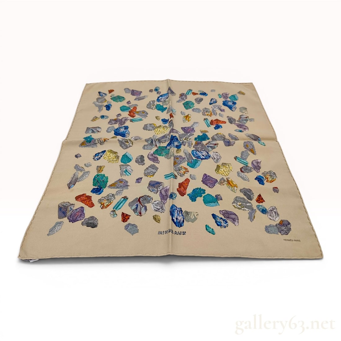 Hermes Mineraux Silk Gavroche Pocket Square: A 100 percent silk pocket square, also known as a gavroche, from Hermes featuring the Mineraux pattern. The design displays an assortment of colorful mineral, crystal, and gemstone specimens in shades
