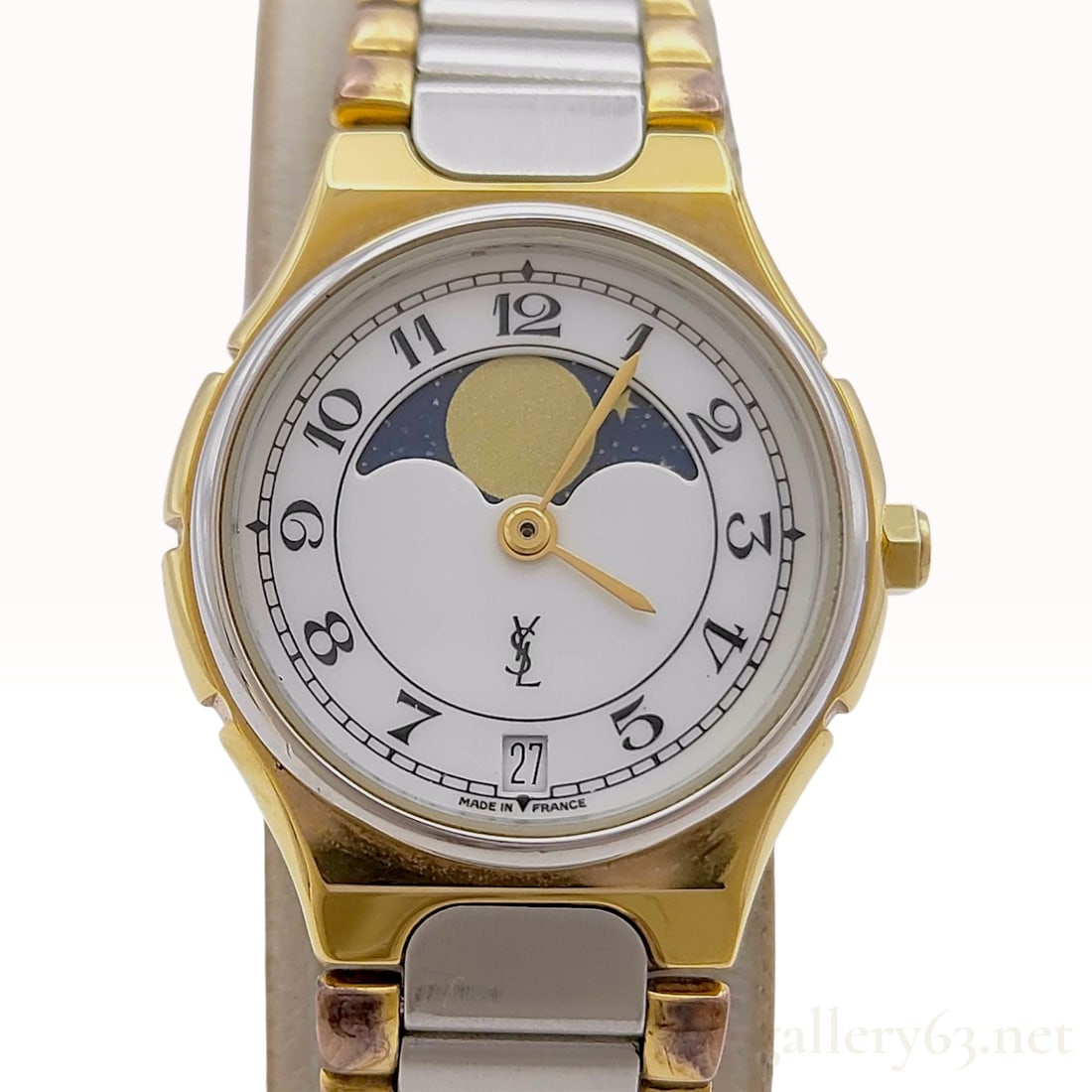 Yves Saint Laurent Moon Phase Date Reference 382470 Quartz Wristwatch: A vintage ladies wristwatch manufactured by Yves Saint Laurent featuring a round two-tone case with a stainless steel back. The white dial displays black Arabic numeral hour markers, a moon phase comp