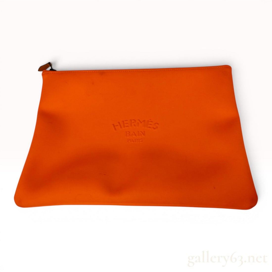Hermes Orange Neobain Pouch, Medium Model: This Hermes Neobain pouch is crafted from a technical fabric in the brand's signature orange color. The front of the flat, rectangular case features an embossed logo reading HERMES BAIN PARIS. The ite