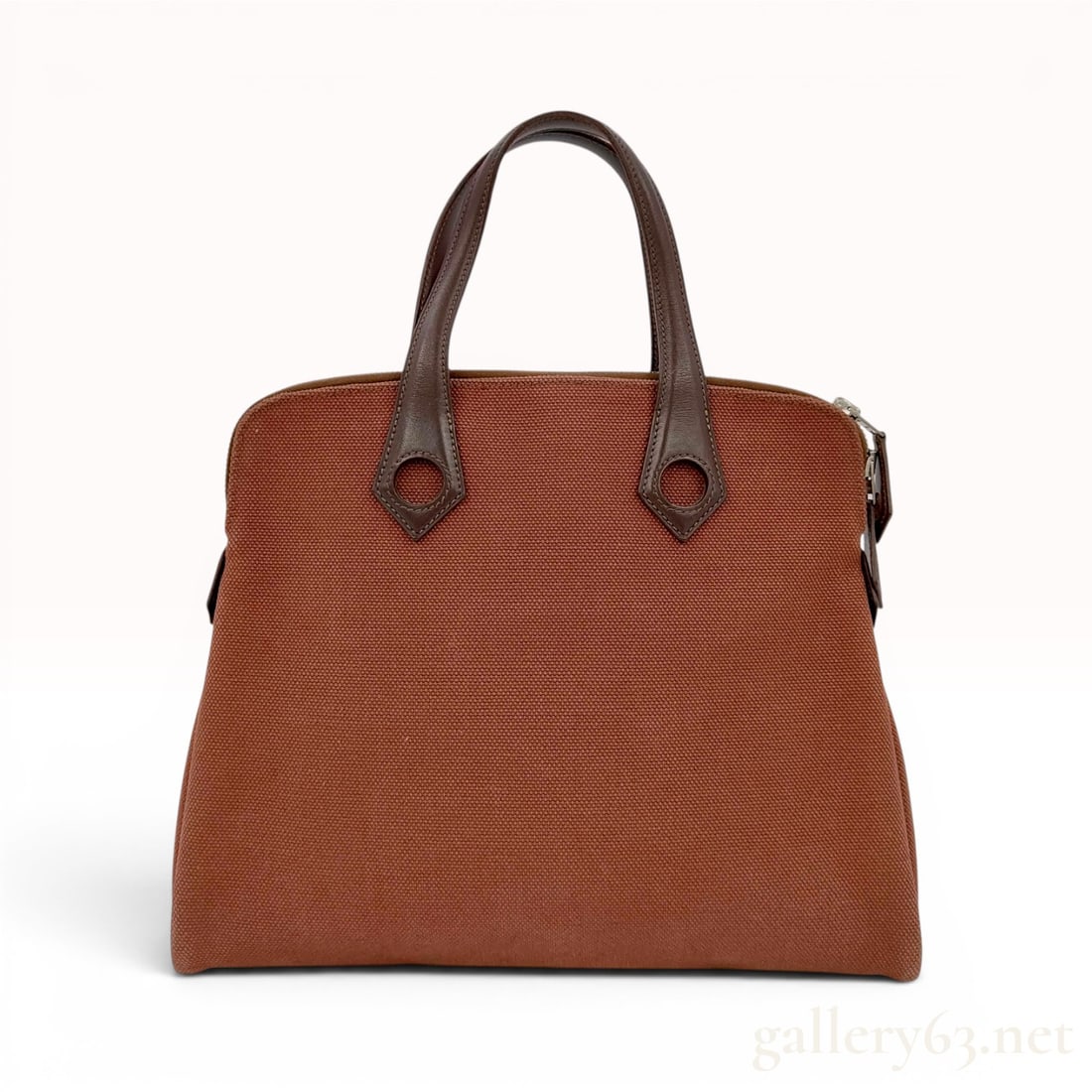 Hermes Heeboo Handbag in Rust Toile Canvas and Brown Leather: This Hermes Heeboo handbag is crafted with a rust-colored toile canvas body and dark brown leather trim. The bag features a trapezoidal silhouette and signature double rolled leather handles attached 