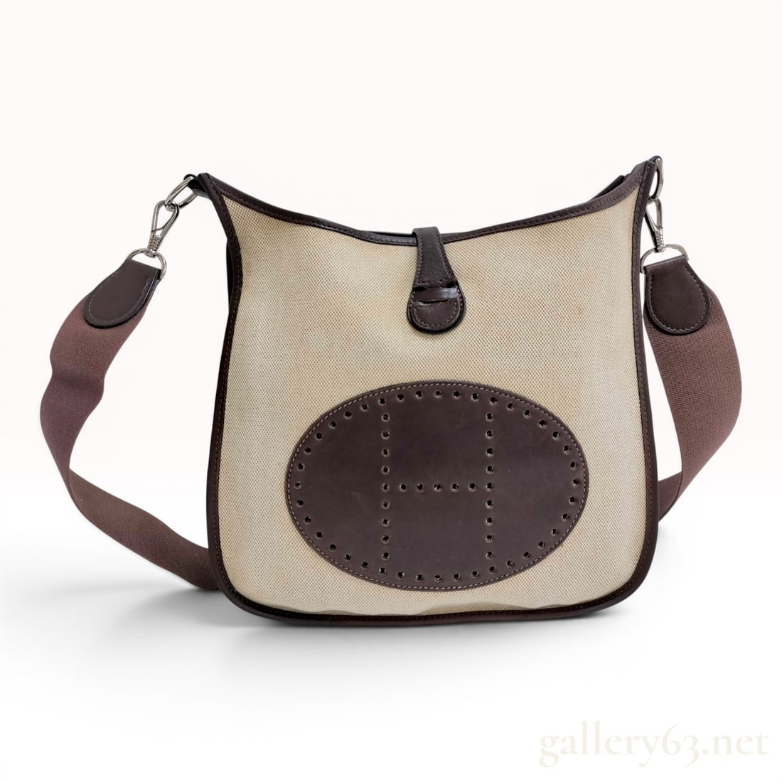 Hermes Evelyne I PM Toile and Leather Shoulder Bag: This Hermes Evelyne I PM shoulder bag is crafted from natural cream-colored toile canvas and dark brown leather. The front of the bag features the signature perforated H logo set within a dark brown l