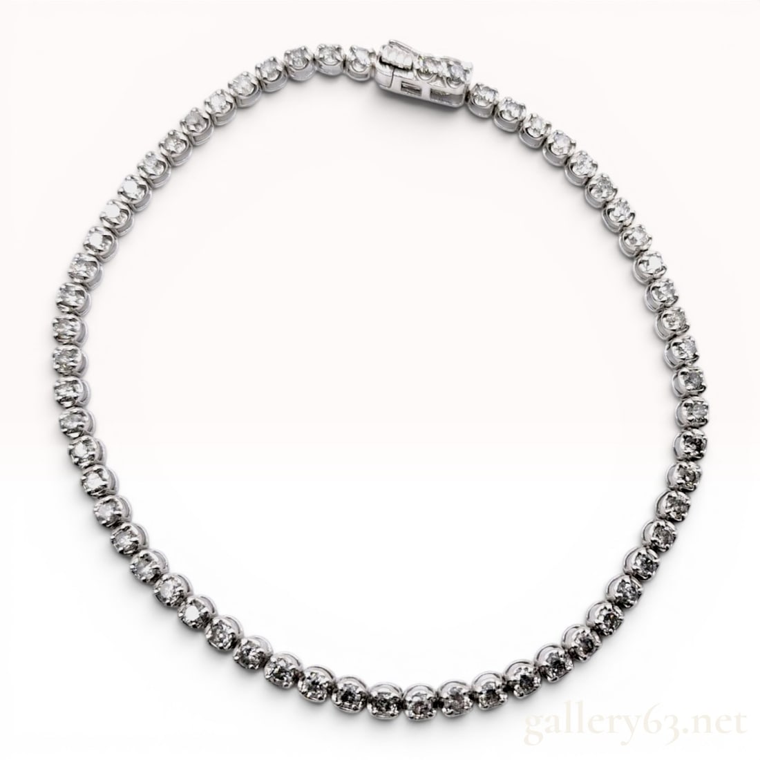 2.00ctw Diamond and 18-Karat White Gold Tennis Bracelet: This tennis bracelet is crafted in 18-karat white gold and features a continuous line of round brilliant cut diamonds. Each diamond is individually set in a four-prong articulated circular link. The p