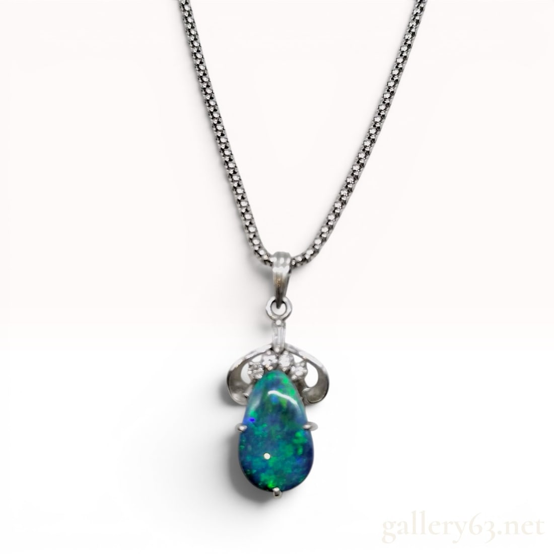 Australian Black Opal and Diamond Platinum Pendant on 18K White Gold Chain: This pendant necklace features a pear-shaped black opal cabochon secured in a four-prong platinum setting. The opal exhibits a vibrant play-of-color with dominant flashes of emerald green and cobalt b