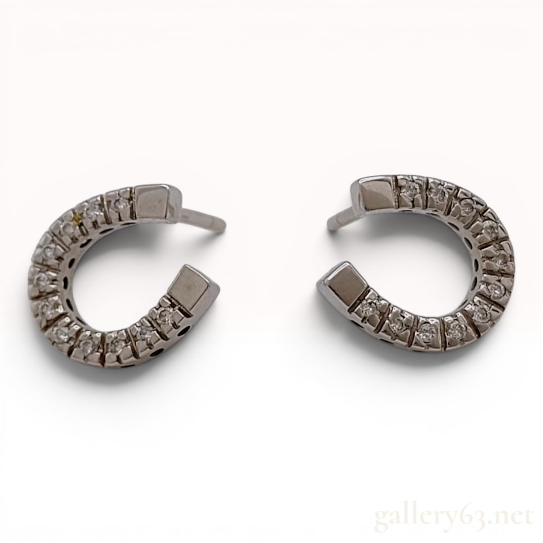 A Pair of Star Jewelry 18k White Gold and Diamond Horseshoe Stud Earrings: A matched pair of horseshoe-shaped stud earrings by the maker Star Jewelry. The earrings are constructed from 18k white gold and feature a total of twenty-six round-cut clear stones, with thirteen sto
