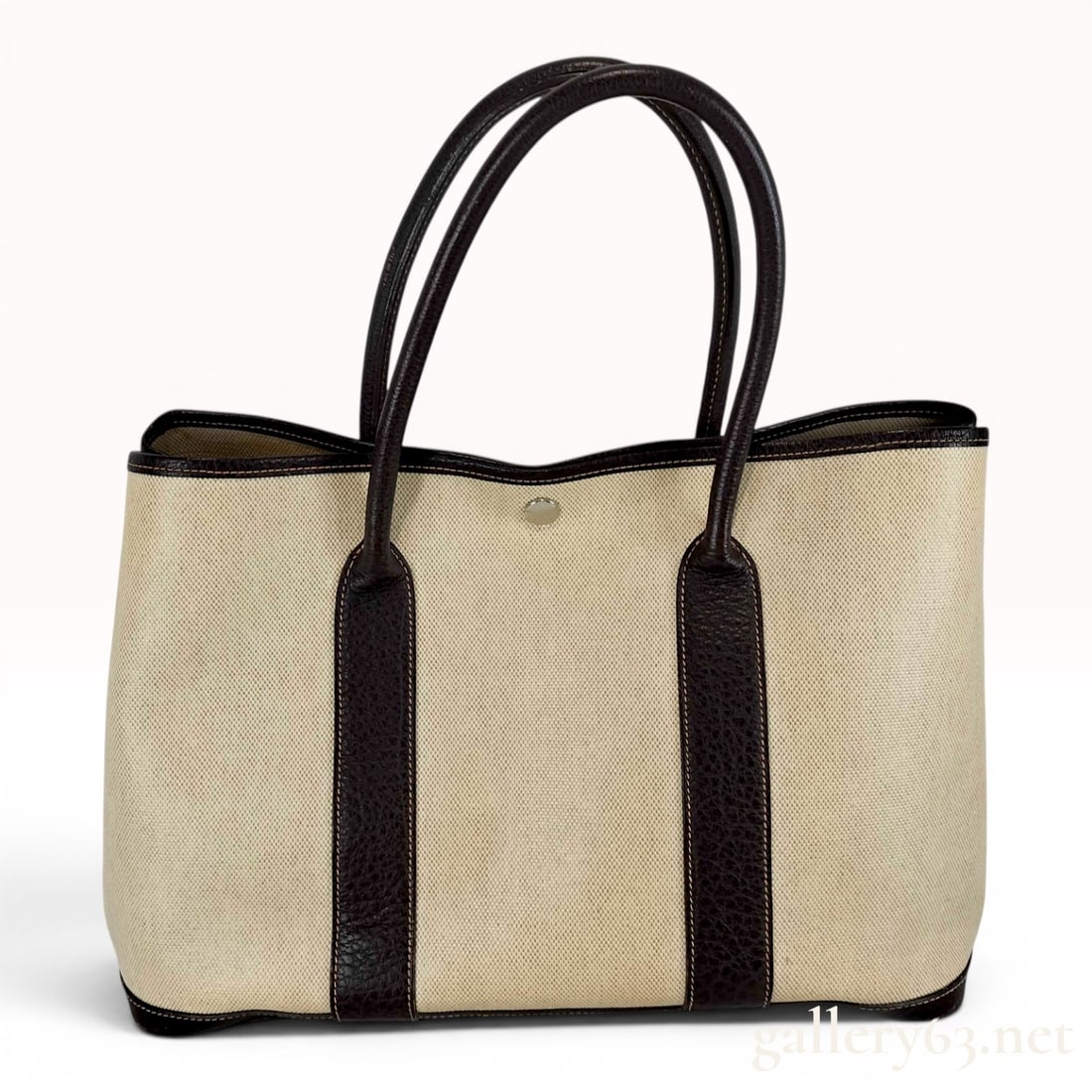 Hermes Toile and Leather Garden Party 36 Tote Bag: This Hermes Garden Party 36 (PM) tote bag is crafted with a beige canvas toile body and dark brown grained leather handles, trim, and a reinforced leather base. The bag features a silver-tone snap but