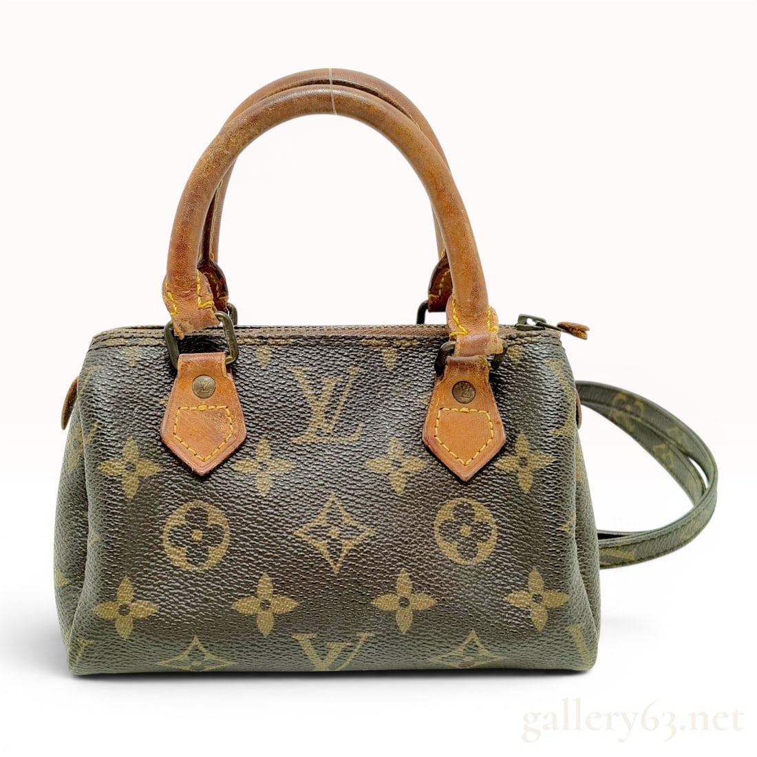 Louis Vuitton Monogram Mini Speedy HL Handbag with Strap: This Louis Vuitton Mini Speedy HL is constructed from signature monogram coated canvas with natural cowhide leather trim and dual rolled handles. It is a miniature iteration of the iconic Speedy bag a