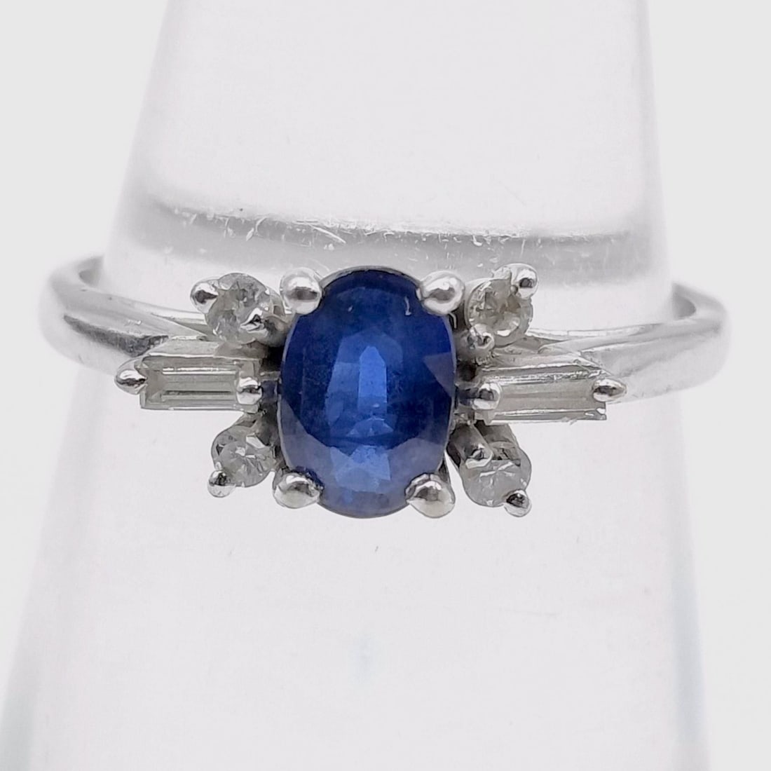 14 Karat White Gold Sapphire and Diamond Ring: This ring is crafted in 14 karat white gold and features a central oval-cut blue sapphire. The sapphire is held in a four double-prong setting and exhibits a deep blue color with visible natural inclu