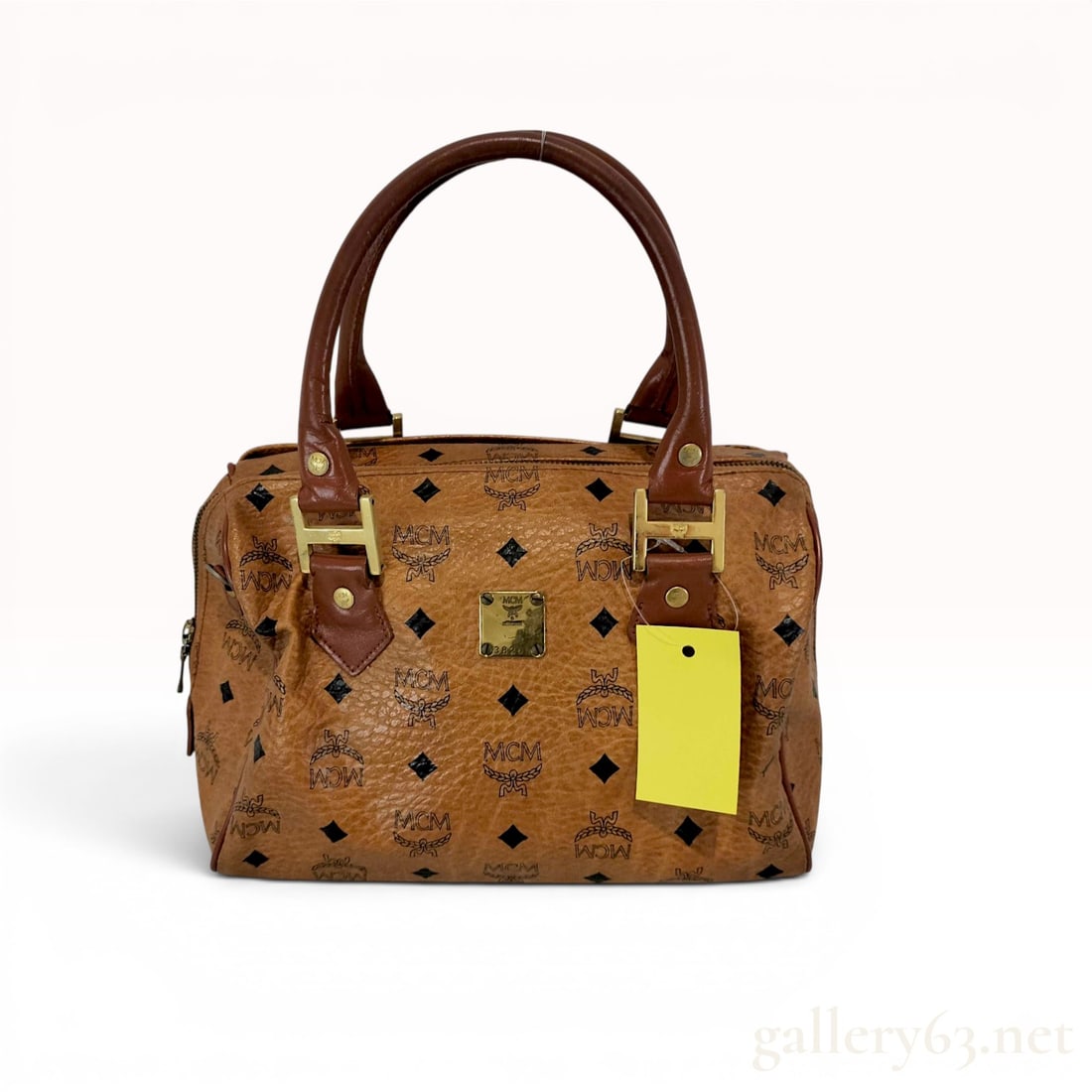 MCM Vintage Cognac Visetos Monogram Boston Satchel Bag: This vintage MCM (Modern Creation Munchen) Boston-style satchel is constructed from the brand's signature cognac Visetos monogram coated canvas, featuring a repeating pattern of the MCM logo, laurel w