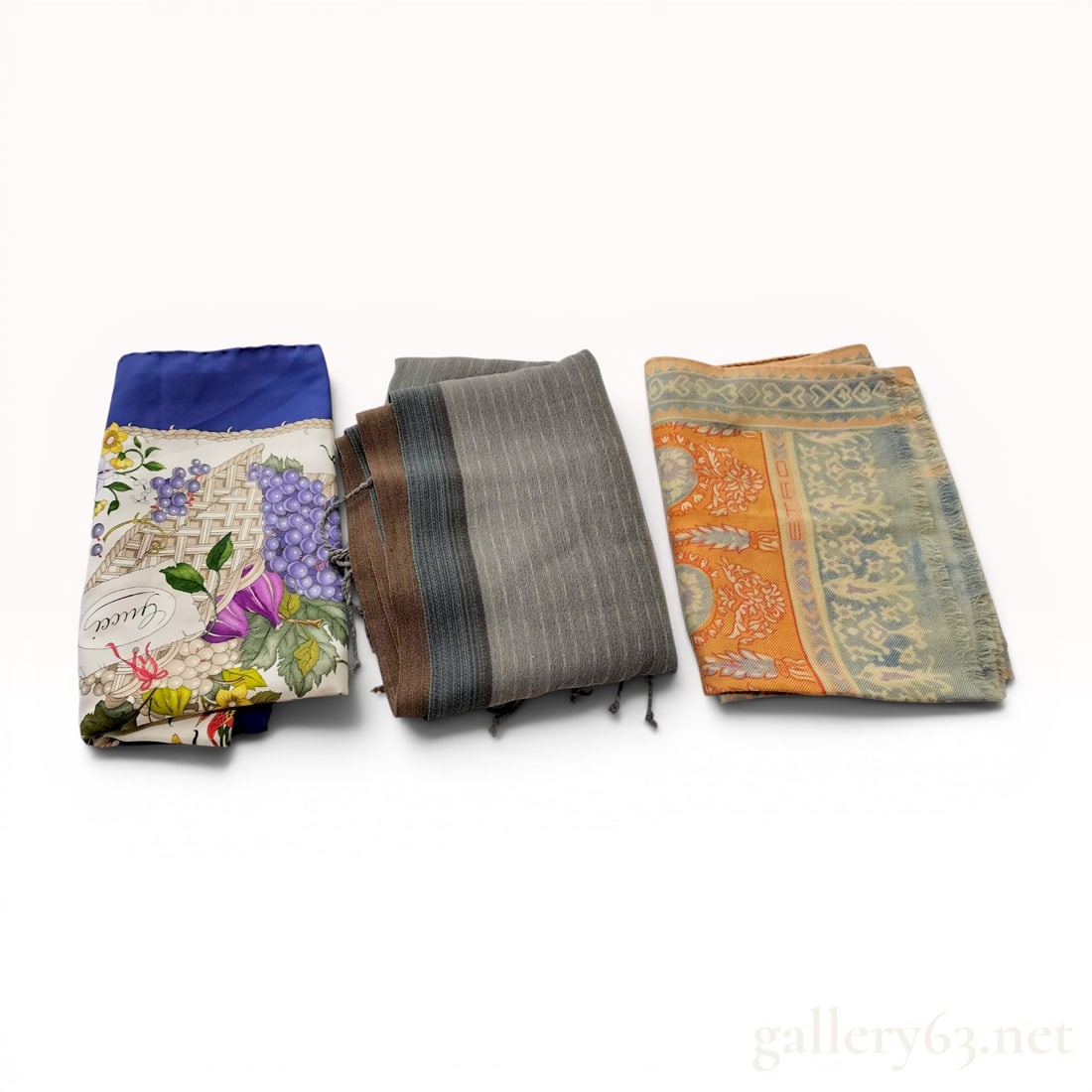 A Trio of Designer Scarves Including Gucci, Etro, and Jurgen Lehl: This lot features a trio of designer scarves from Gucci, Etro, and Jurgen Lehl. The first item is a square silk scarf by Gucci decorated with the Flora pattern, which consists of various flowers, frui